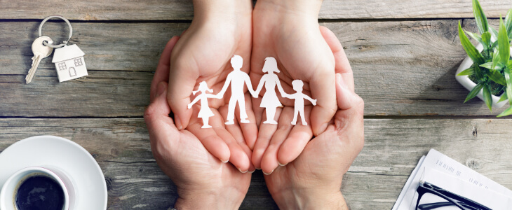 image of open hands holding cut of of family with 2 children