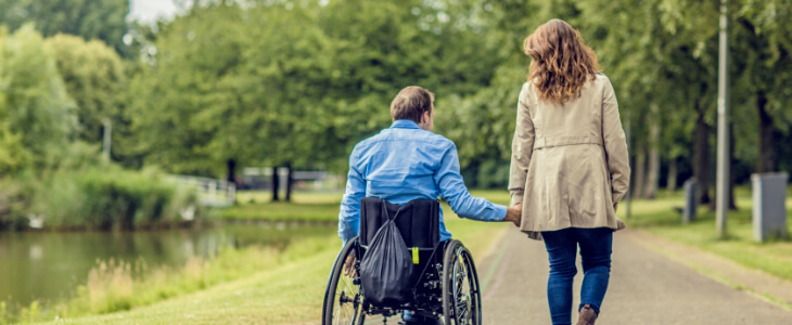 image of man in wheelchair holding hands with woman while walking